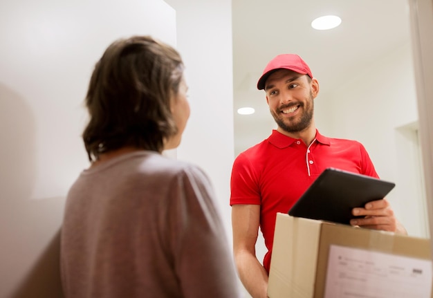 concepto de entrega, correo, personas y envío - hombre feliz con computadora de tablet pc y cajas de paquetes en casa del cliente