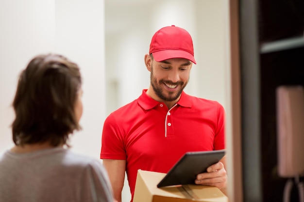 concepto de entrega, correo, personas y envío - hombre feliz con computadora de tablet pc y cajas de paquetes en casa del cliente