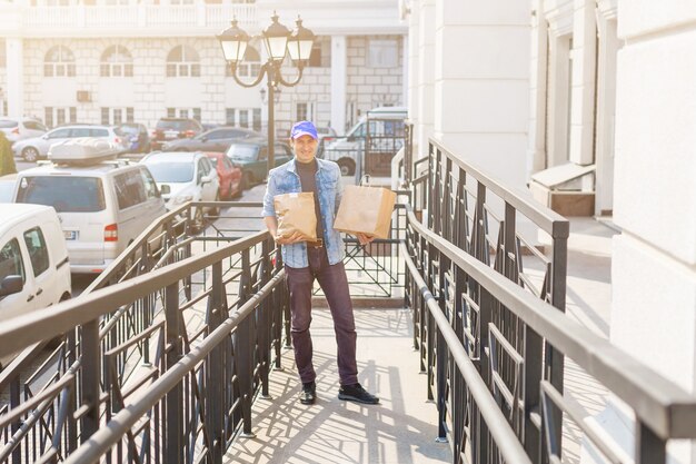 concepto de entrega, correo y personas - hombre entregando café y comida en una bolsa de papel desechable a la casa del cliente