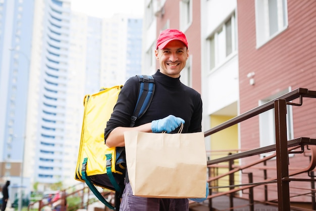 concepto de entrega, correo y personas - hombre feliz entregando alimentos en una bolsa de papel desechable a la casa del cliente