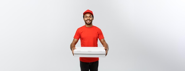 Concepto de entrega Retrato de un apuesto repartidor de pizza afroamericano aislado en el espacio de copia de fondo del estudio gris