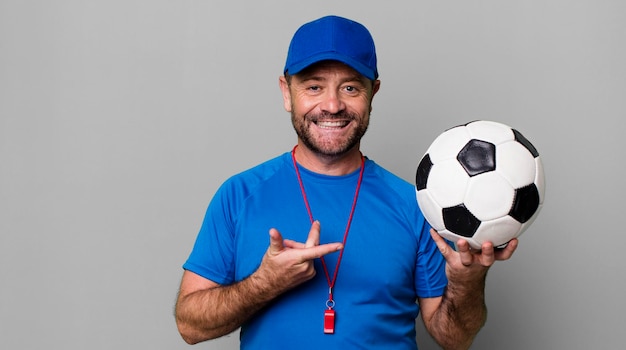 Concepto de entrenador deportivo de hombre de mediana edad con una pelota de fútbol