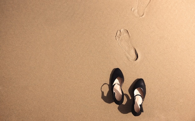 concepto de equilibrio trabajo-vida. Mujer de negocios quitarse los zapatos de trabajo en la playa de arena, caminar hasta el mar