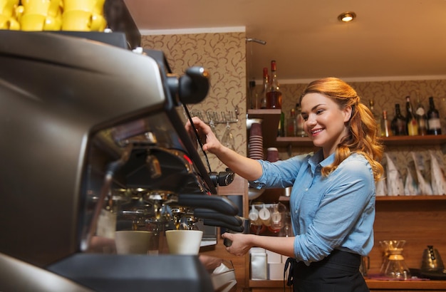 concepto de equipo, cafetería, personas y tecnología - mujer barista haciendo café a máquina en la cafetería o en la cocina del restaurante