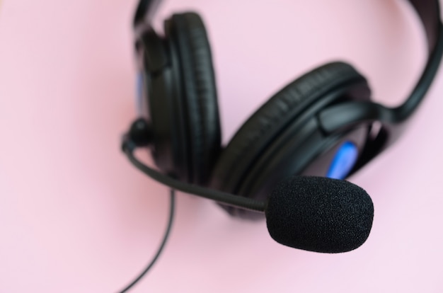 Foto concepto de escuchar música. auriculares negros se encuentra en fondo rosa