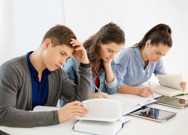 concepto de escuela y educación - grupo de estudiantes cansados con cuadernos en la escuela