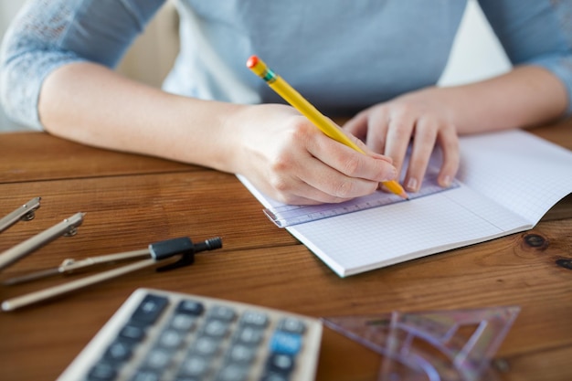 concepto de escuela, educación, personas y aprendizaje - cierre de manos de estudiantes o mujeres con regla y línea de dibujo a lápiz en el cuaderno