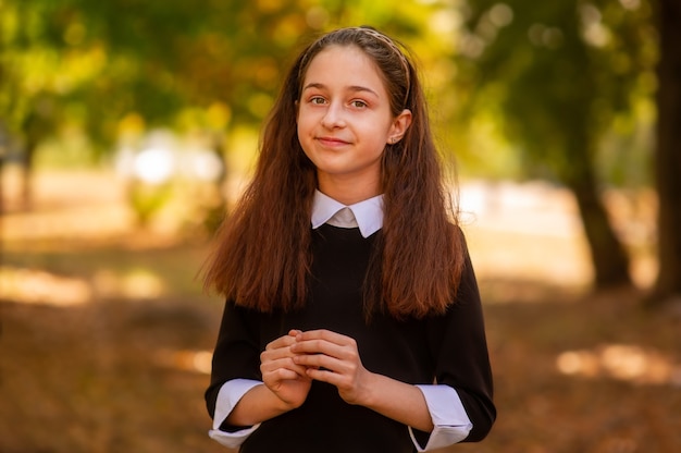 Concepto de escuela. Niña de 11 o 12 años con un vestido en el fondo de la naturaleza en otoño.