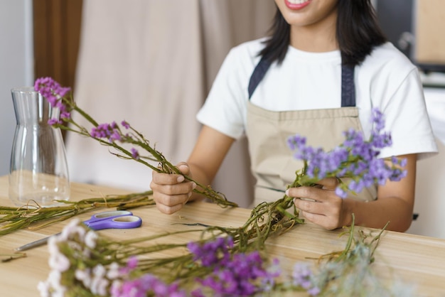 Concepto de estilo de vida acogedor Mujer joven sentada en la cocina y arreglando flores en un jarrón sobre la mesa