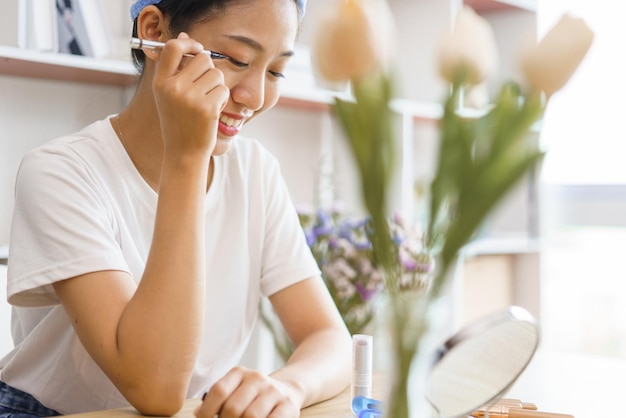 Concepto de estilo de vida acogedor Mujer joven en turbante después de la ducha y aplicar delineador de ojos en el párpado para maquillarse