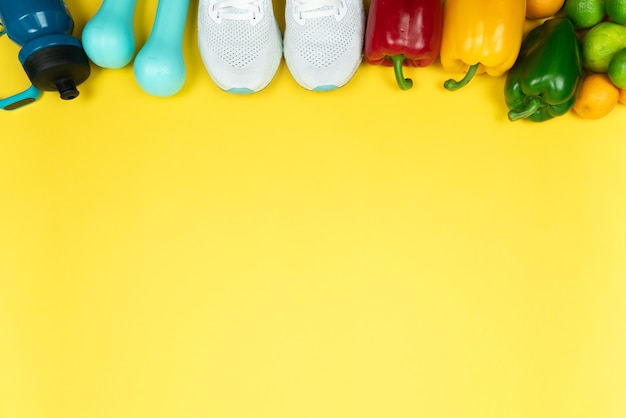 Concepto de estilo de vida, comida y deporte saludable. equipo de atleta y frutas y verduras frescas sobre fondo amarillo.