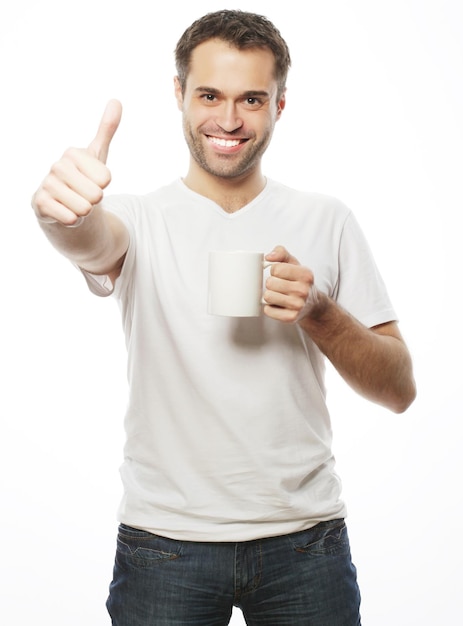 Concepto de estilo de vida, comida y personas: joven casual sosteniendo una taza blanca con café o té.