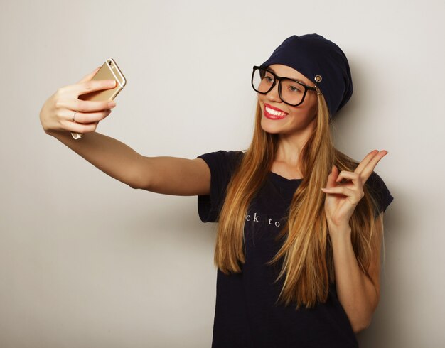 Concepto de estilo de vida, felicidad, emocional y personas: chica bonita hipster tomando selfie.