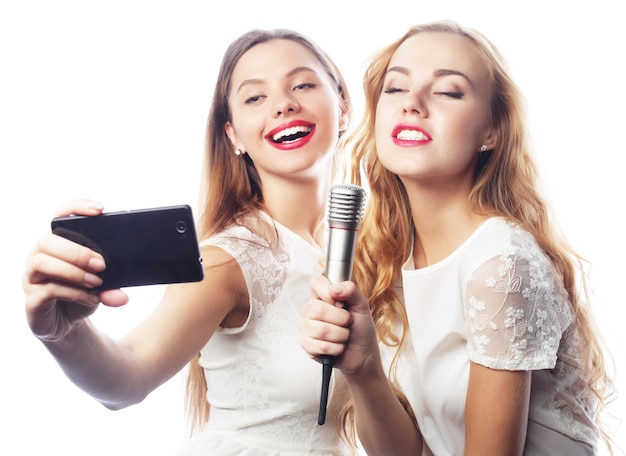 Concepto de estilo de vida, felicidad, emocional y personas: chicas de belleza con un micrófono cantando y haciendo selfie