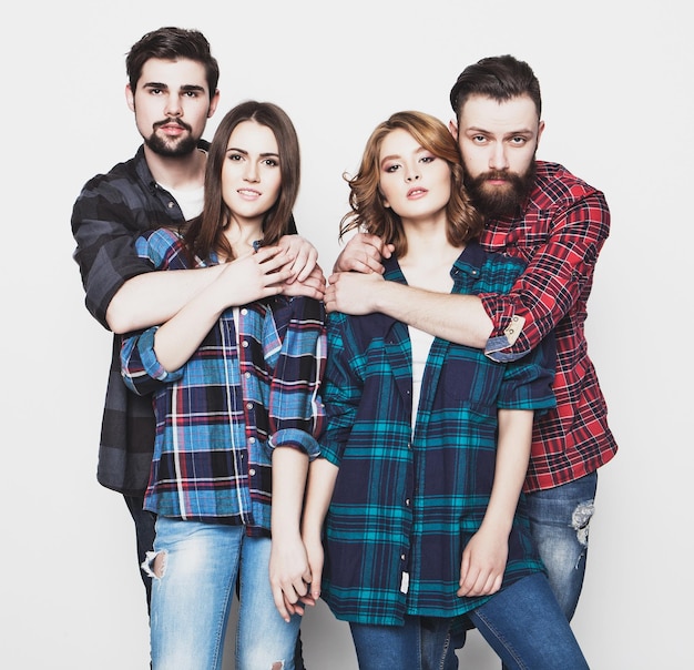 Concepto de estilo de vida, felicidad y personas: atractivo grupo de hombres y mujeres jóvenes felices. Estilo hipster. Foto de estudio sobre fondo blanco. Tonificación especial de moda.