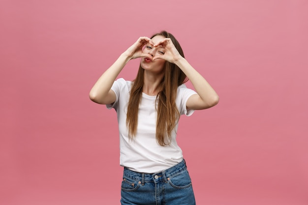 Concepto de estilo de vida: hermosa mujer atractiva en camisa blanca haciendo un símbolo de corazón con sus manos