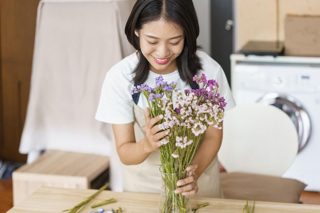 Concepto de estilo de vida hogareño Mujer joven cuidar flores frescas en jarrón sobre la mesa en la cocina