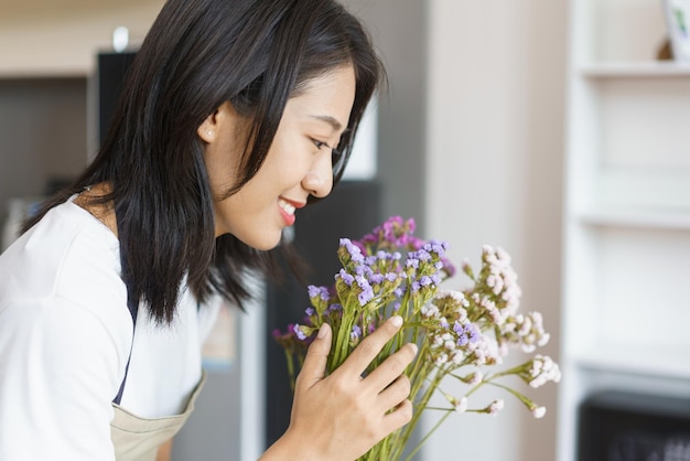 Concepto de estilo de vida hogareño Mujer joven cuidar flores frescas en jarrón sobre la mesa en la cocina