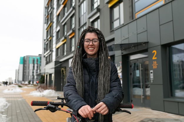 Foto concepto de estilo de vida joven mujer europea con dreadlocks informales peinado montar en bicicleta