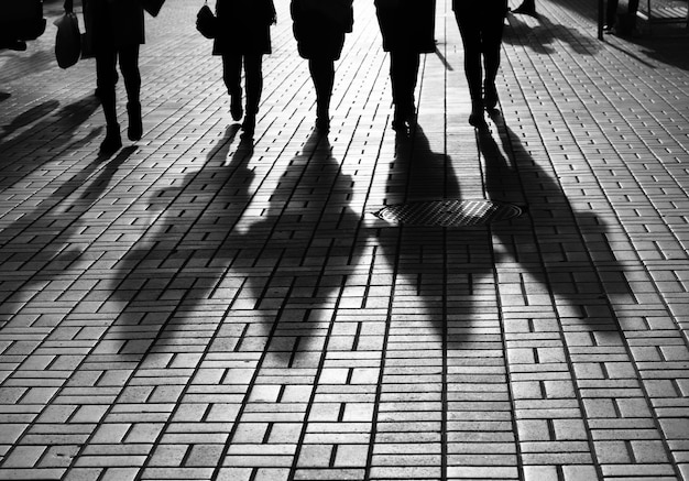 Concepto de estilo de vida. Luces y sombras en la ciudad. Siluetas de personas caminando por las calles de una gran ciudad e iluminadas por luz de fondo. Sombras de gente caminando por la calle a la luz del atardecer.