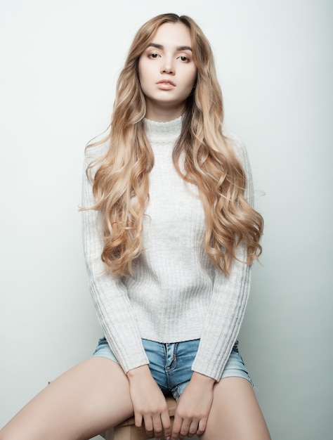 Concepto de estilo de vida, moda y personas: hermosa mujer rizada con ropa casual, posando sobre fondo blanco