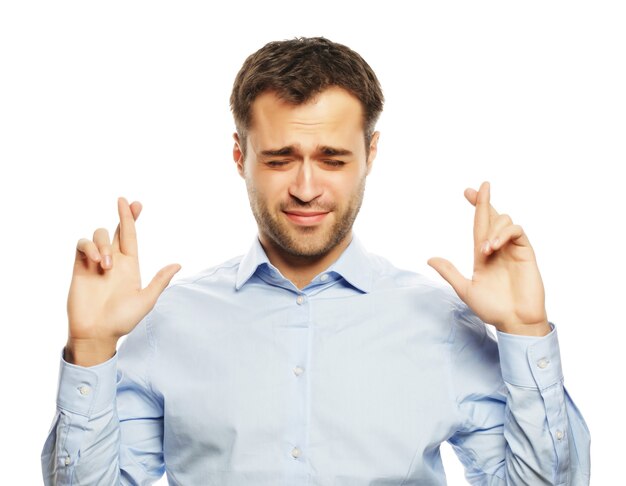 Concepto de estilo de vida, negocios y personas: hombre de negocios en camisa manteniendo los dedos cruzados mientras está de pie contra el fondo blanco.