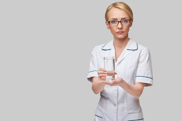 Concepto de estilo de vida o alimentación saludable - mujer médico sosteniendo y un vaso de agua dulce clara