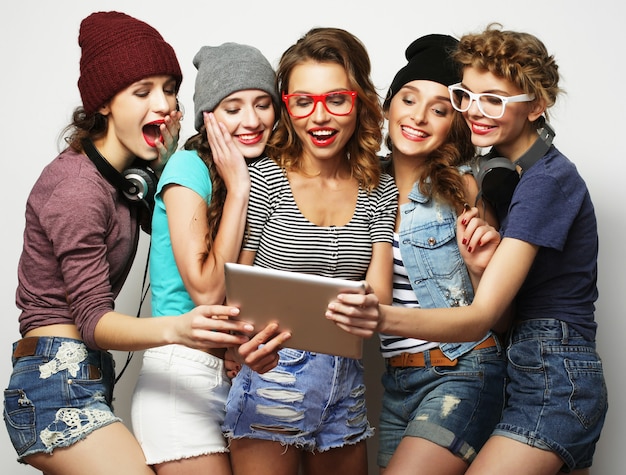 Concepto de estilo de vida y personas: cinco amigas hipster tomando selfie con tableta digital, foto de estudio sobre fondo gris