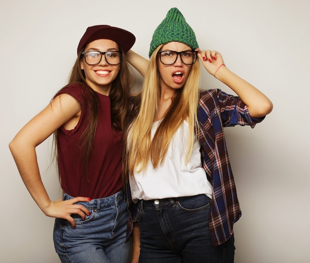 Concepto de estilo de vida y personas: dos amigas jóvenes de pie juntos y divertirse. Mirando a la cámara.