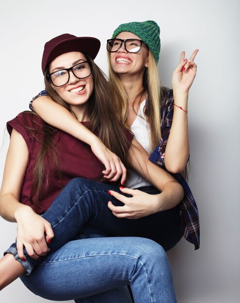 Concepto de estilo de vida y personas: dos amigas jóvenes de pie juntos y divertirse. Mirando a la cámara.