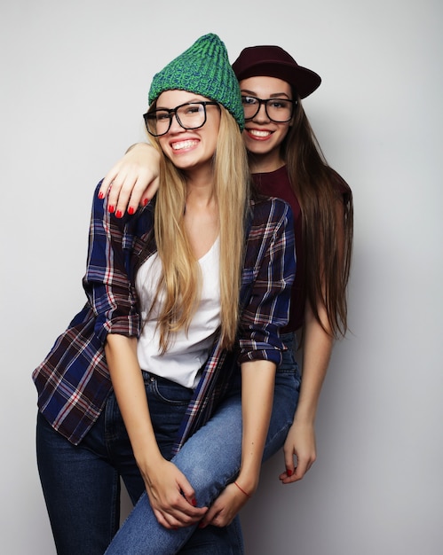 Concepto de estilo de vida y personas: dos amigas jóvenes de pie juntos y divertirse. Mirando a la cámara.