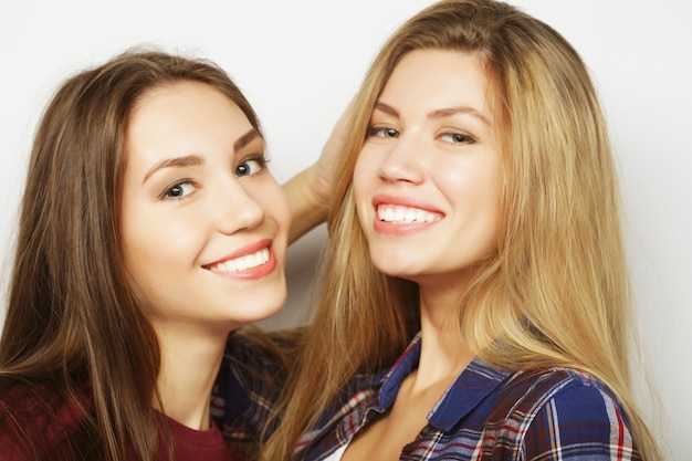 Concepto de estilo de vida y personas: dos amigas jóvenes de pie juntos y divertirse. Mirando a la cámara.