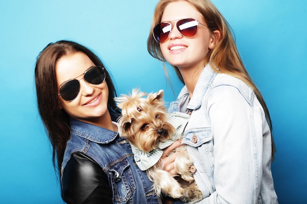 Concepto de estilo de vida y personas Dos jóvenes amigas de pie juntas y sosteniendo perro