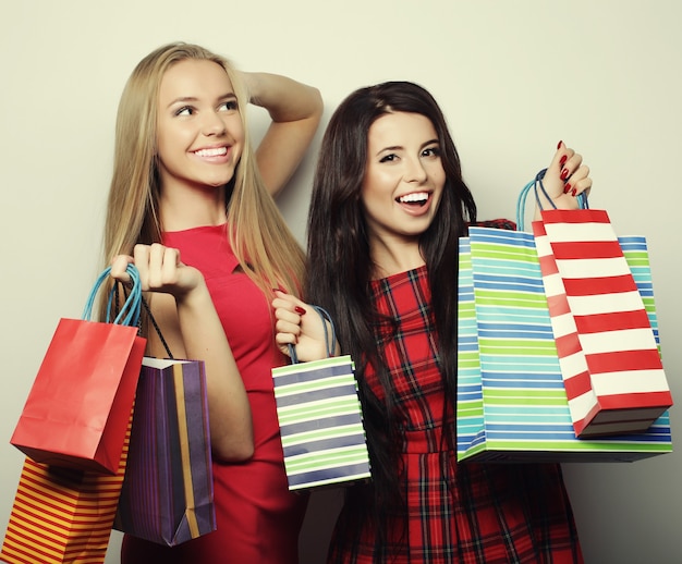 Concepto de estilo de vida y personas: dos mujeres jóvenes con vestido rojo con bolsas de la compra. Gran venta.