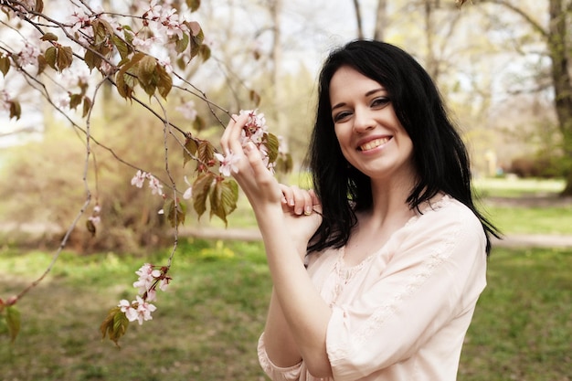 Concepto de estilo de vida y personas Hermosa mujer joven en el jardín de flores Sakura y primavera