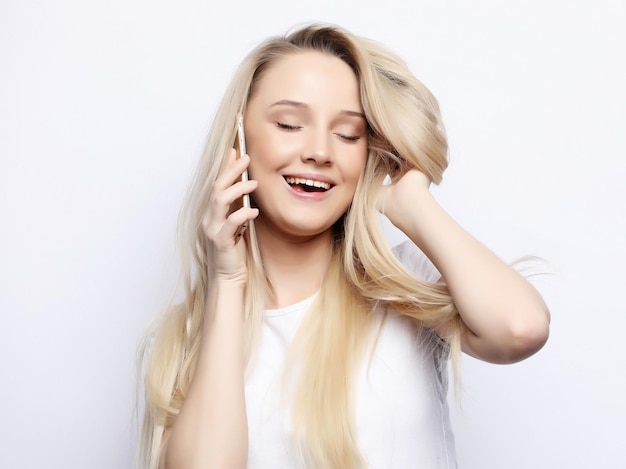 Concepto de estilo de vida y personas Hermosa mujer rubia feliz está hablando por teléfono y tocándose el pelo