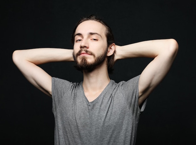 Concepto de estilo de vida y personas Retrato de hombre joven y guapo con barba sobre fondo oscuro