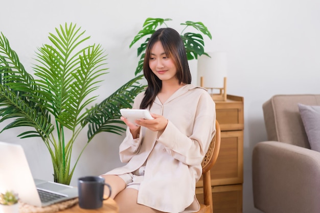 Concepto de estilo de vida de relajación Mujer asiática joven que usa calculadora para calcular las ventas en línea en casa