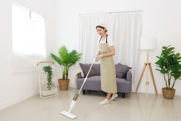 Concepto de estilo de vida en la sala de estar Mujer asiática joven limpiando el piso con aspiradora