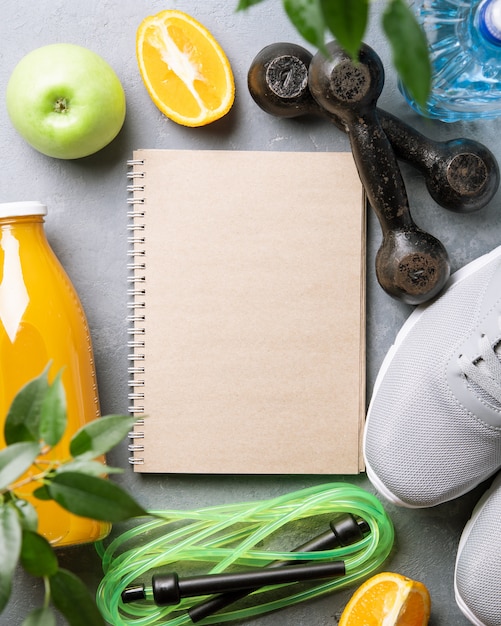 Concepto de estilo de vida saludable. Diario de salud. Zapatillas de deporte, agua, pesas con una manzana verde