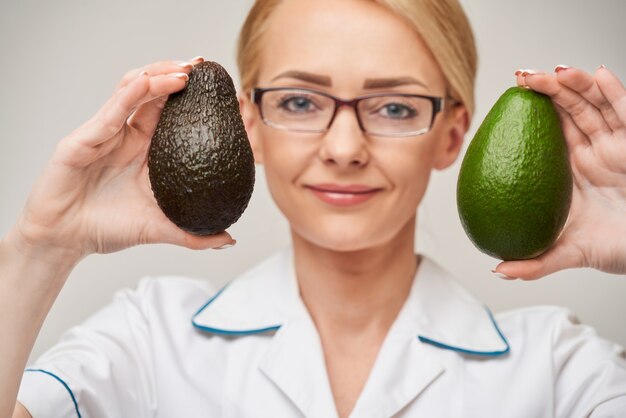 concepto de estilo de vida saludable médico nutricionista - sosteniendo fruta de aguacate orgánico