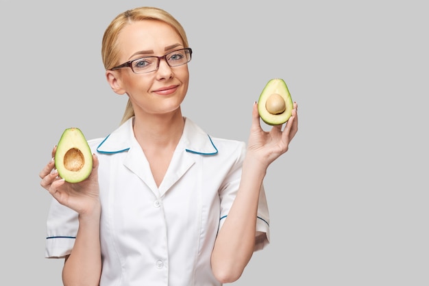 concepto de estilo de vida saludable médico nutricionista - sosteniendo fruta de aguacate orgánico