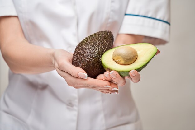 Concepto de estilo de vida saludable médico nutricionista - sosteniendo fruta de aguacate orgánico