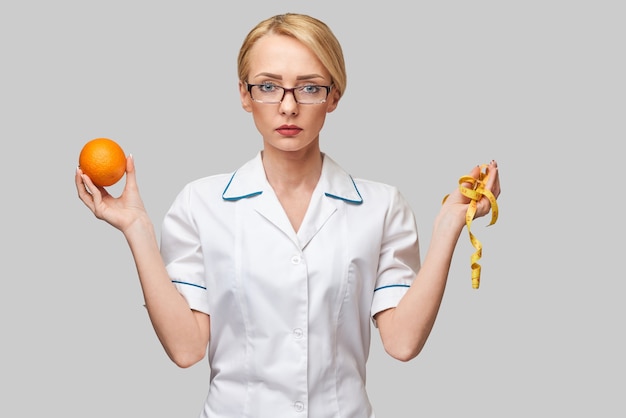 Concepto de estilo de vida saludable médico nutricionista - sosteniendo fruta naranja fresca orgánica y cinta métrica