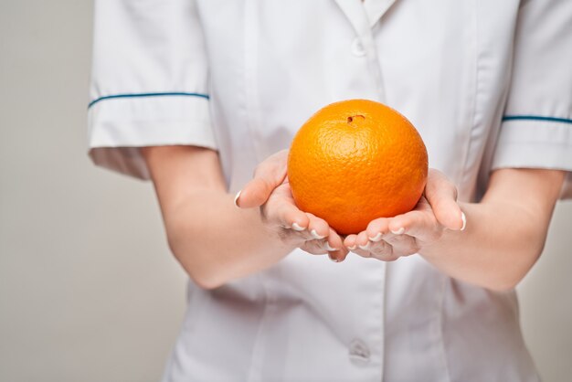 concepto de estilo de vida saludable médico nutricionista - sosteniendo fruta naranja