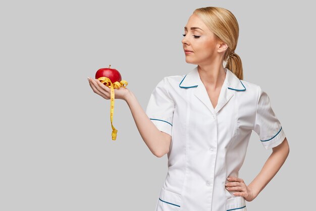 concepto de estilo de vida saludable médico nutricionista - sosteniendo manzana roja orgánica y cinta métrica