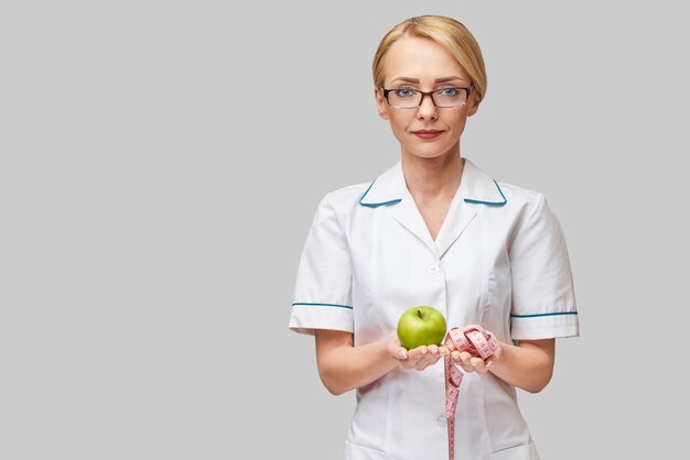 Concepto de estilo de vida saludable médico nutricionista - sosteniendo manzana verde fresca orgánica y cinta métrica