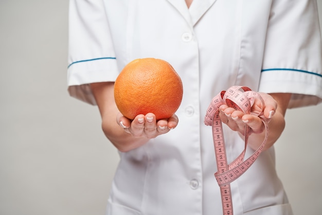 Concepto de estilo de vida saludable médico nutricionista - sosteniendo pomelo orgánico o fruta naranja y cinta métrica