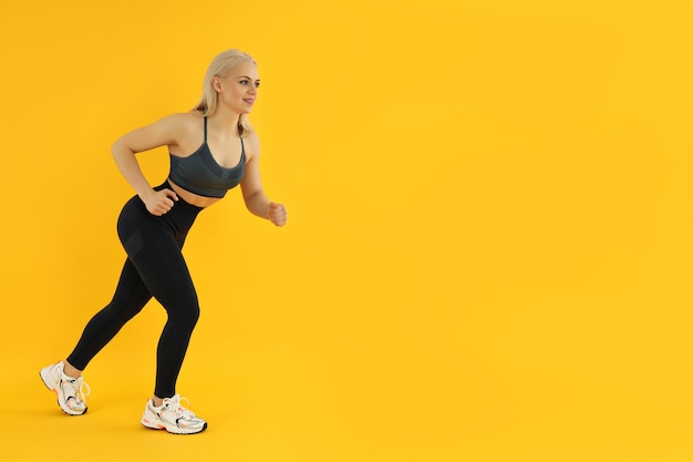 Concepto de estilo de vida saludable con mujer deportiva sobre fondo amarillo