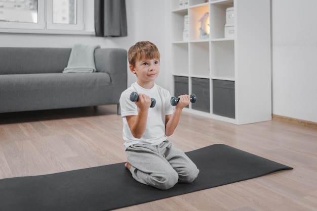 Concepto de estilo de vida saludable para niños Retrato de niño caucásico haciendo ejercicio con pesas